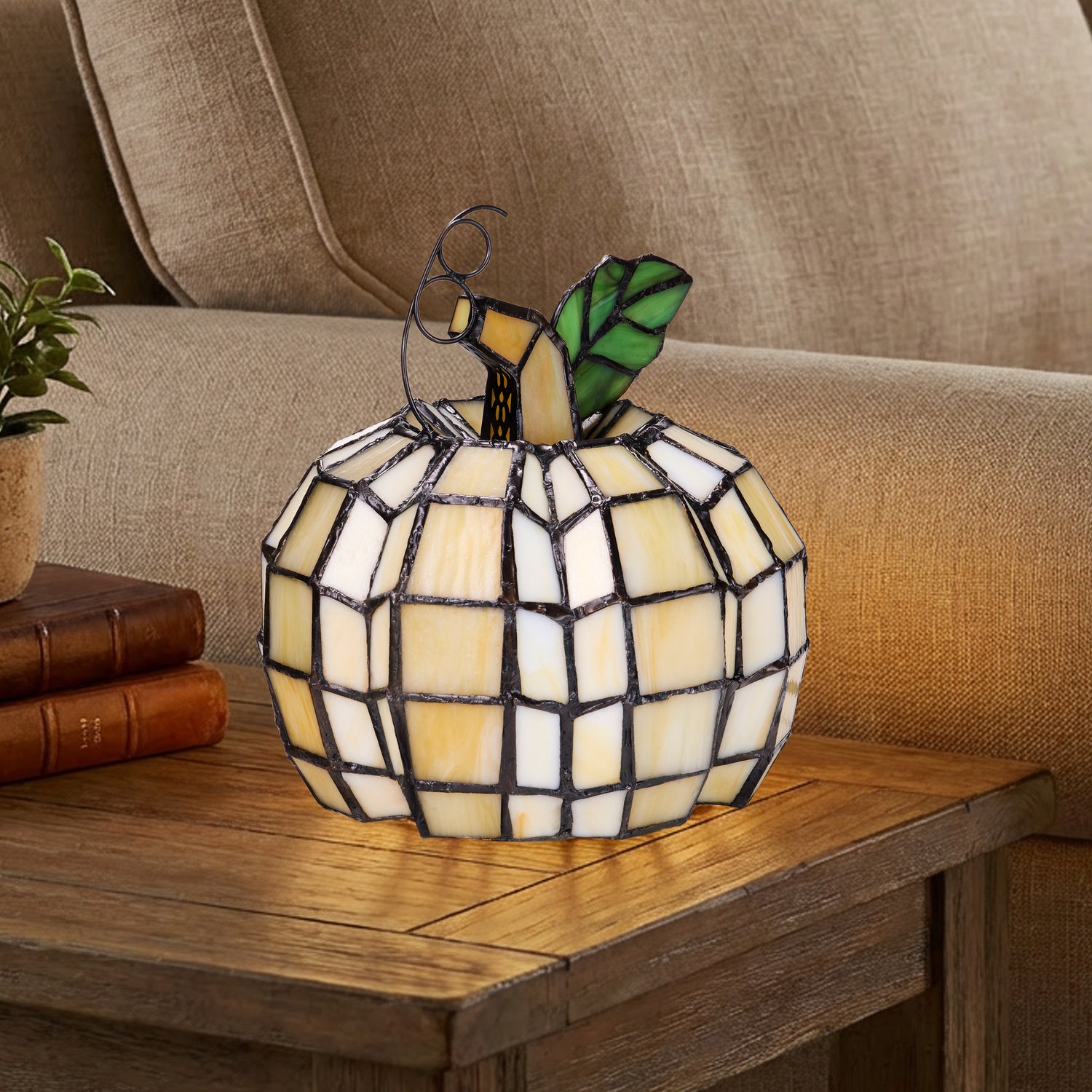 9"H Patch the Pumpkin Stained Glass Accent Lamp, placed on a wooden side table in front of a beige sofa.